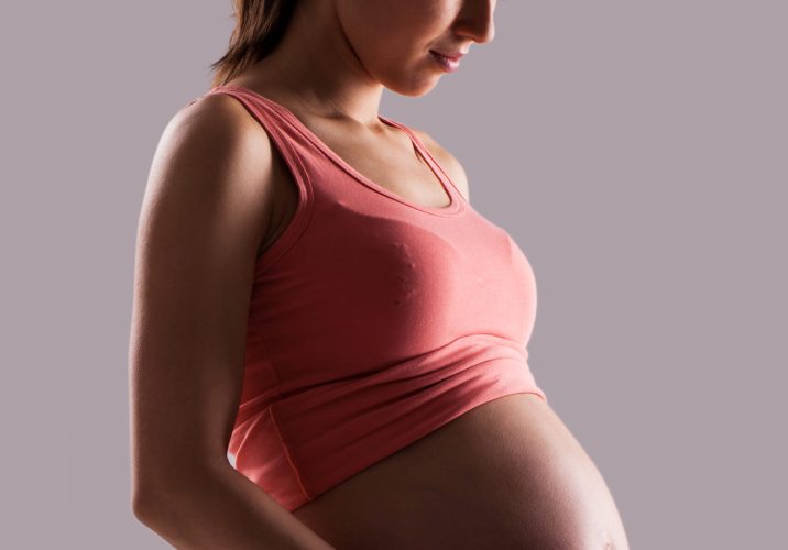 Beautiful pregnant woman isolated over grey background