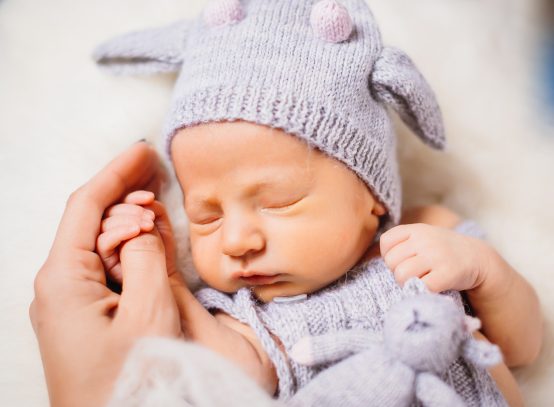 Little baby in blue suit lies on white fluffy pillow