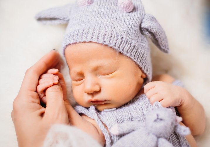 Little baby in blue suit lies on white fluffy pillow